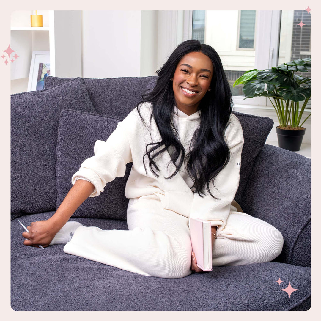 Female founder Lisa smiling while sitting on a couch holding the female founders journal.