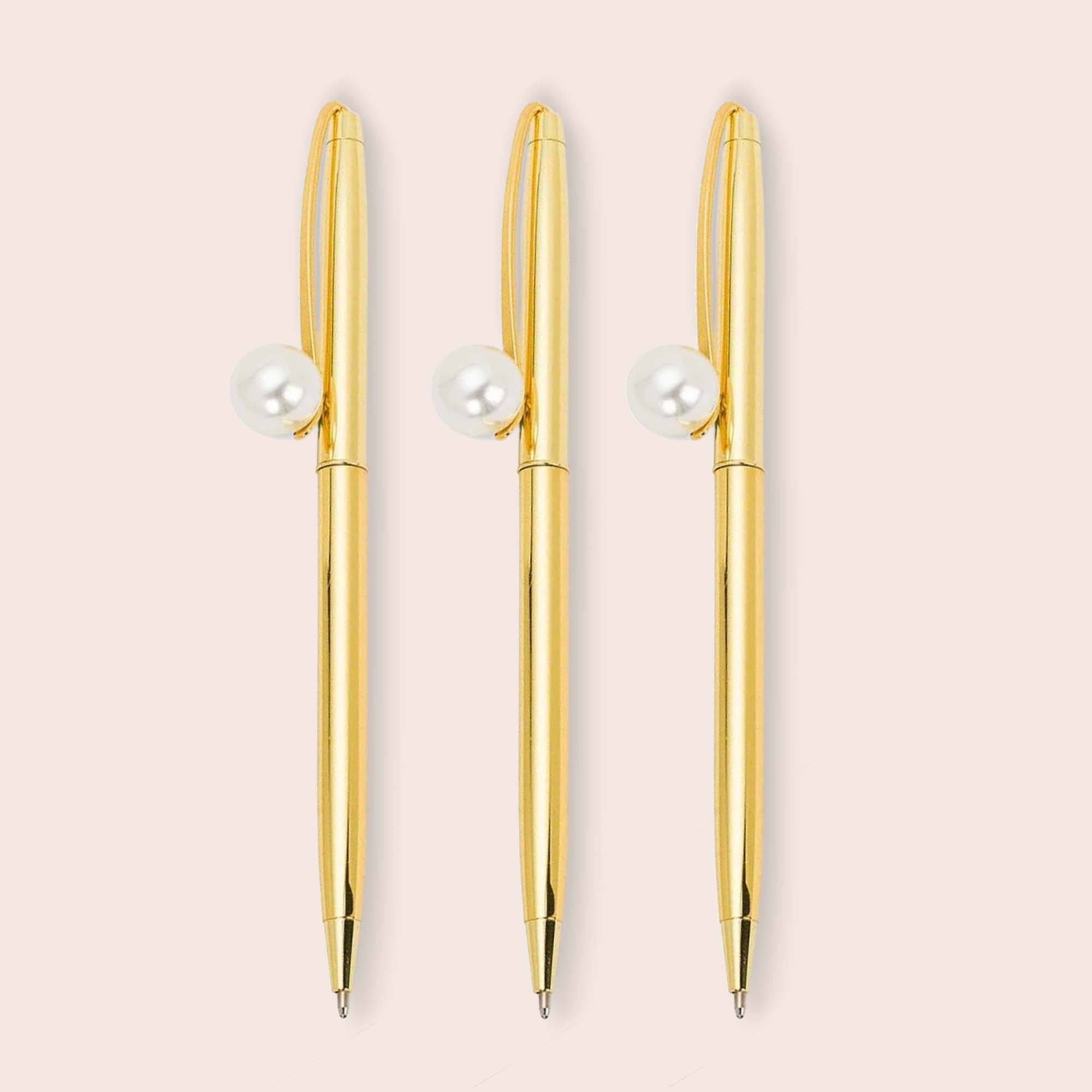 A bundle of 3 golden pens with a pearl at the top 