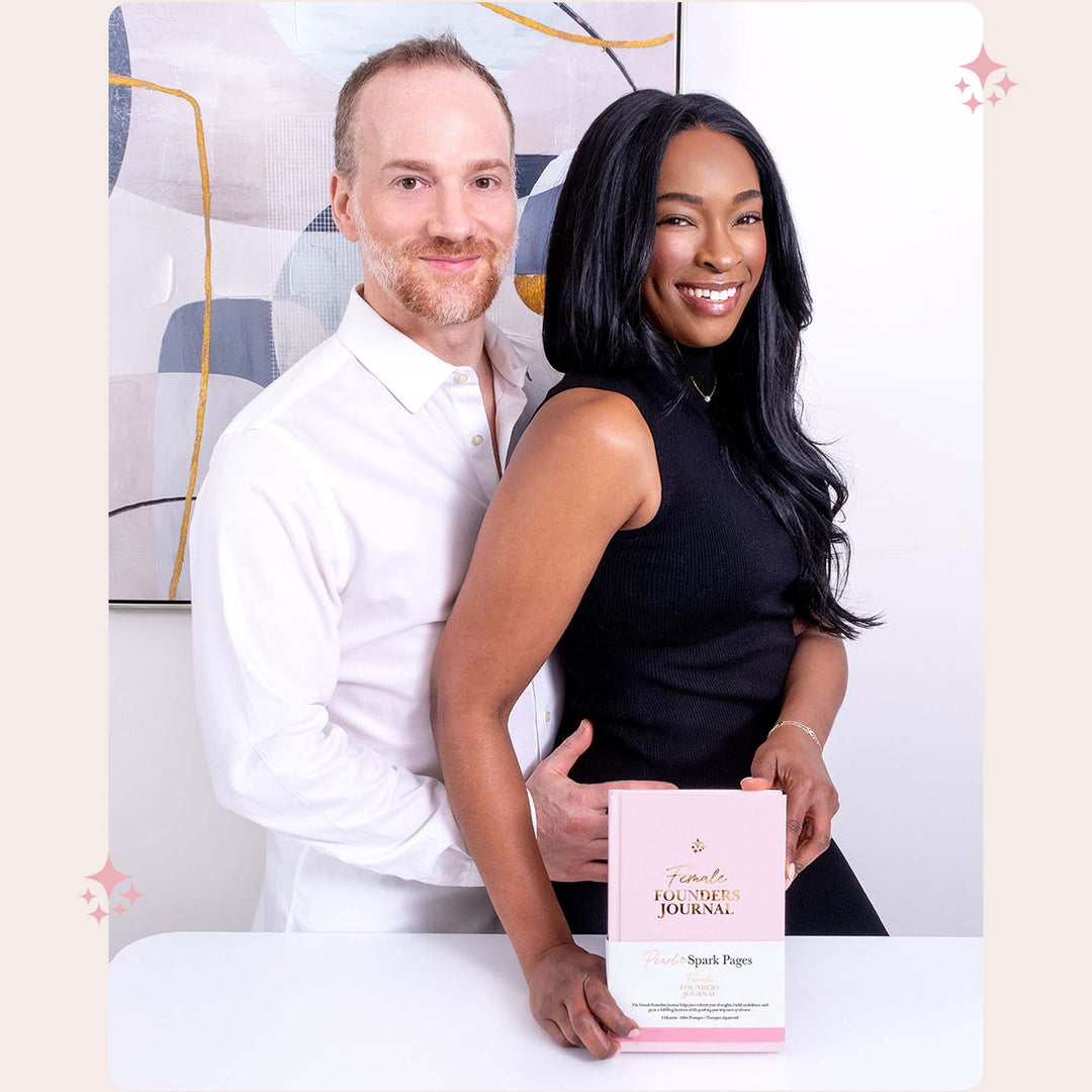 Lisa, a Black female founder and CEO, and Steve, her COO, smiling behind their desk holding the Female Founders Journal, celebrating women-led entrepreneurship.